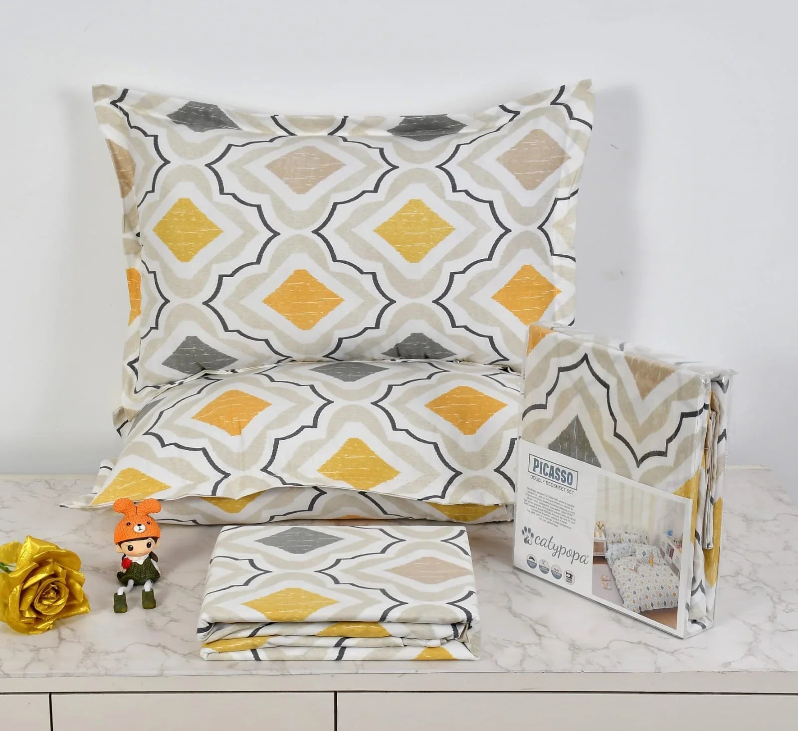 Moroccan diamond pattern bedsheet set in yellow, grey and white colors - Picasso collection 3PC cotton bedding set with geometric design by Towelleo.com displayed on white dresser with decorative flowers and packaging
