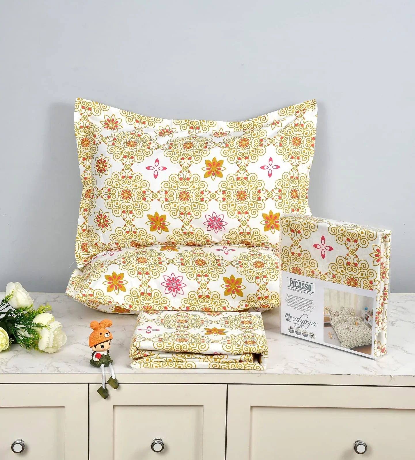 Traditional mandala bedsheet set with gold ornate pattern and colorful floral motifs - Picasso collection 3PC cotton bedding set by Towelleo.com displayed on white dresser with decorative flowers and packaging
