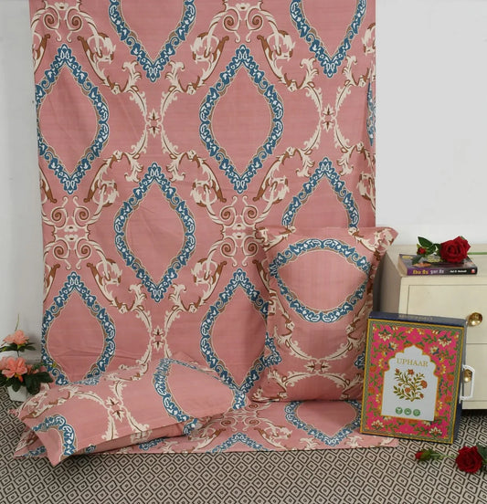 Pink patterned fabric with decorative pillows and a framed picture on a surface.